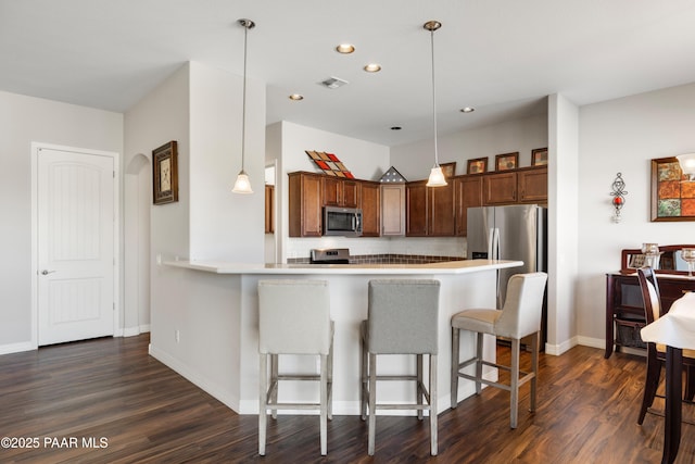 6286 E Livingston Loop, Prescott Valley, AZ 86314 - kitchen with stainless steel appliances, a breakfast bar area, dark wood-type flooring, light countertops, and a peninsula