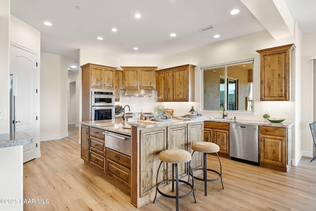 1032 Vantage Point Cir, Prescott, AZ 86301 - kitchen with appliances with stainless steel finishes, a warming drawer, a center island with sink, light wood finished floors, and brown cabinets