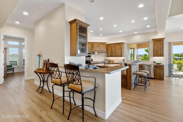 1032 Vantage Point Cir, Prescott, AZ 86301 - kitchen with brown cabinetry, a breakfast bar, dishwasher, light wood-style flooring, and recessed lighting