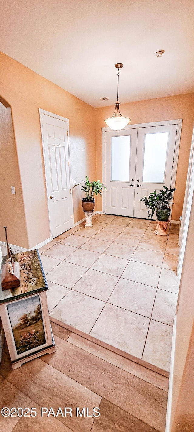 entrance foyer with tile patterned floors and french doors