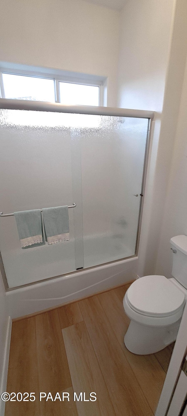 bathroom featuring wood-type flooring, a shower with shower door, and toilet