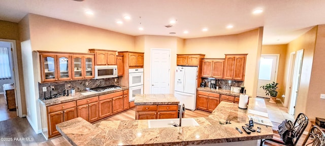 kitchen featuring white appliances, a center island, light hardwood / wood-style floors, and backsplash