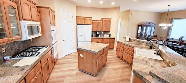 kitchen with sink, tasteful backsplash, decorative light fixtures, white appliances, and a kitchen island