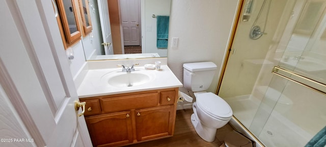 bathroom with hardwood / wood-style floors, vanity, a shower with shower door, and toilet