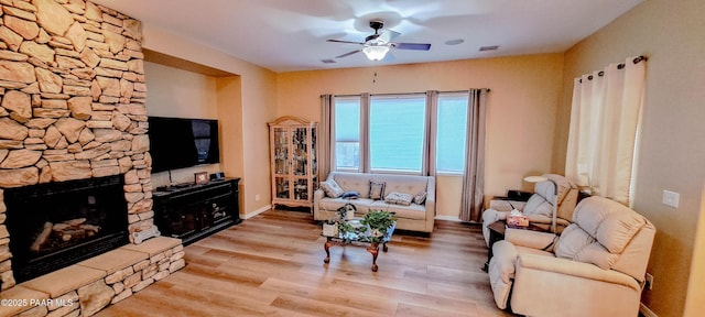 living room with ceiling fan, a fireplace, and light hardwood / wood-style flooring