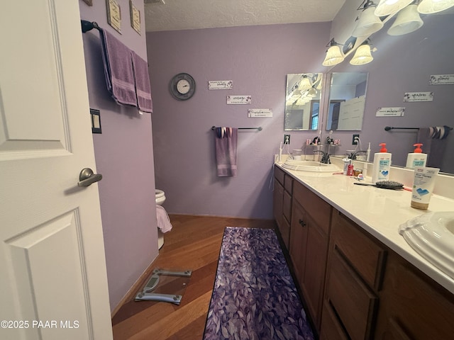 bathroom featuring vanity, hardwood / wood-style flooring, toilet, and a textured ceiling