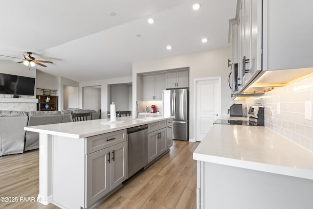 kitchen featuring stainless steel appliances, a kitchen island with sink, and gray cabinets