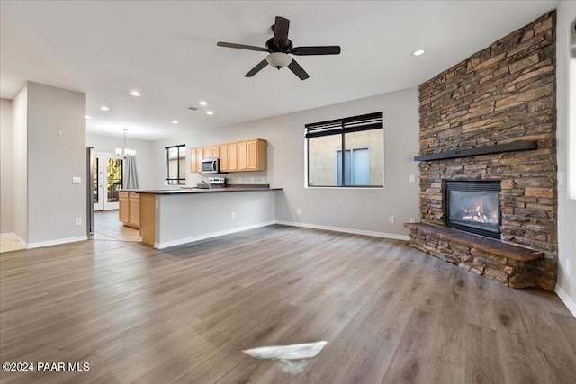 unfurnished living room with a fireplace, light hardwood / wood-style flooring, and ceiling fan with notable chandelier