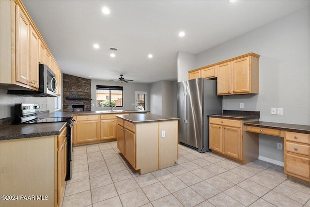 kitchen with a center island, ceiling fan, built in desk, kitchen peninsula, and stainless steel appliances