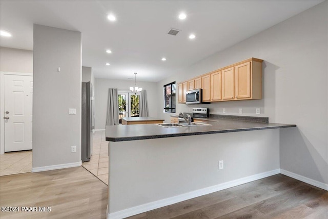 kitchen featuring light hardwood / wood-style floors, kitchen peninsula, sink, and appliances with stainless steel finishes