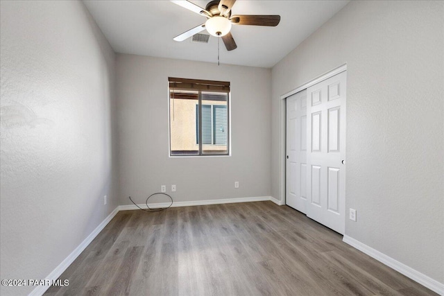 unfurnished bedroom with ceiling fan, a closet, and light wood-type flooring