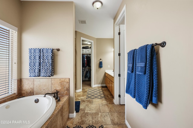 bathroom with vanity and a relaxing tiled tub