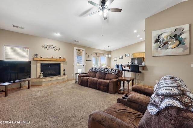 carpeted living room featuring ceiling fan, lofted ceiling, and a tiled fireplace