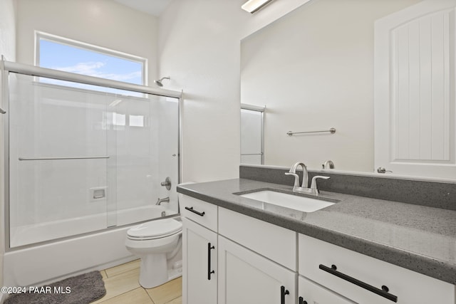 full bathroom with combined bath / shower with glass door, vanity, toilet, and tile patterned flooring