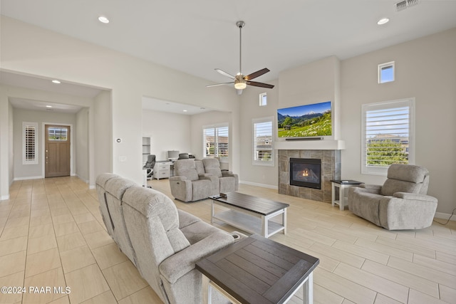 living room featuring a tiled fireplace, a wealth of natural light, and ceiling fan