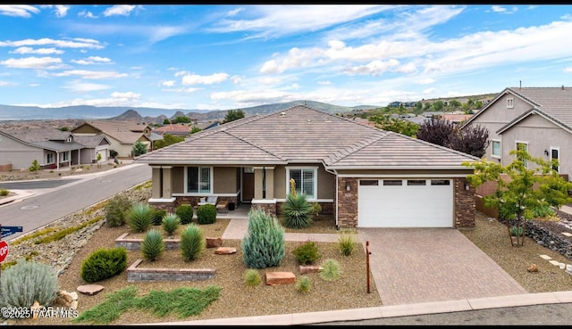 ranch-style home featuring covered porch, a mountain view, and a garage