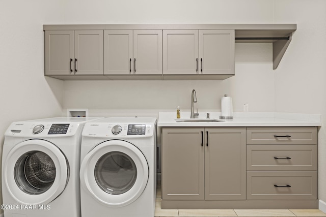 clothes washing area with washer and clothes dryer, cabinets, light tile patterned floors, and sink