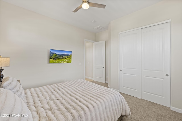 bedroom with ceiling fan, light colored carpet, and a closet