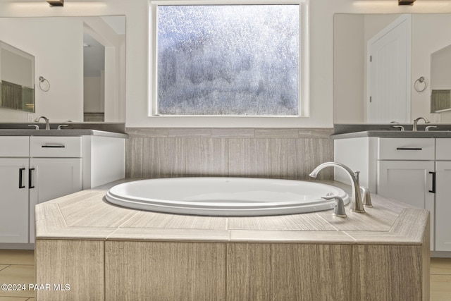 bathroom featuring a relaxing tiled tub, vanity, and a wealth of natural light