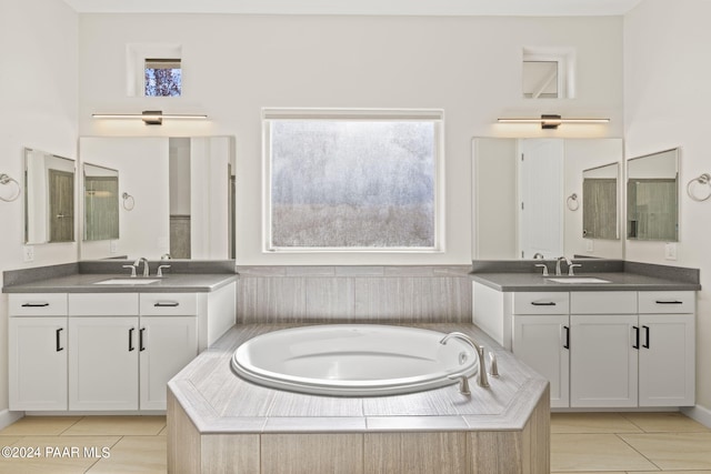 bathroom featuring tile patterned floors, vanity, and a relaxing tiled tub