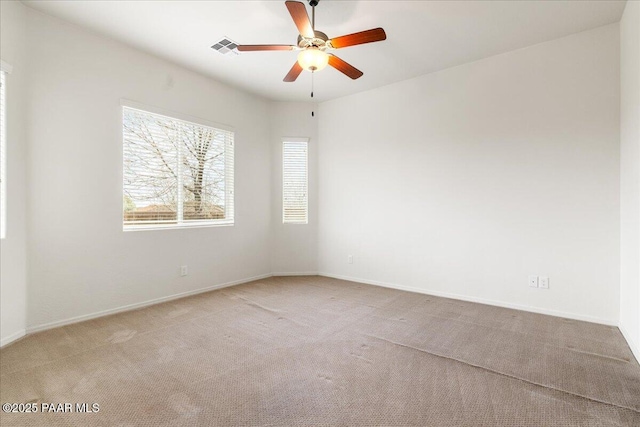 spare room featuring baseboards, carpet floors, ceiling fan, and visible vents