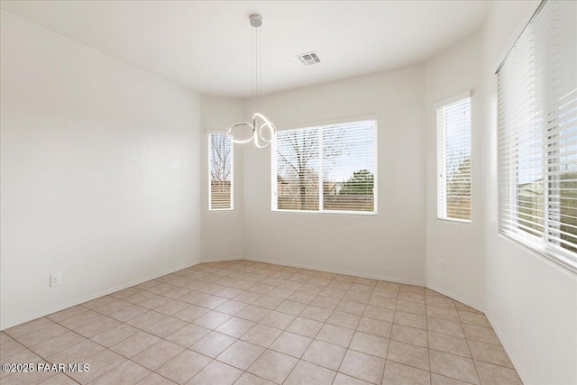 empty room with light tile patterned flooring, baseboards, visible vents, and a notable chandelier