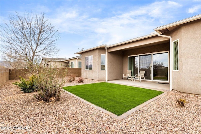 back of property with stucco siding, a fenced backyard, a yard, and a patio area