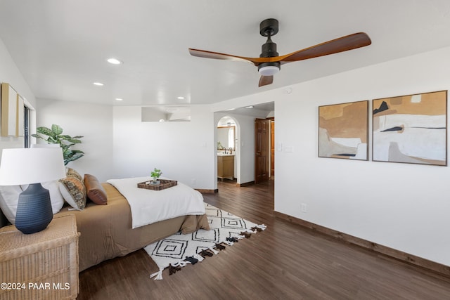 bedroom featuring dark hardwood / wood-style flooring, ensuite bathroom, and ceiling fan