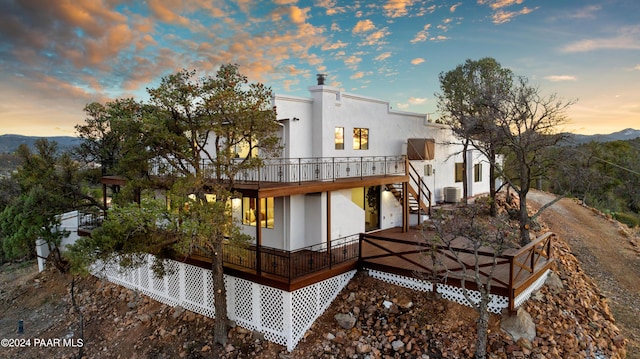 back house at dusk featuring a deck with mountain view and central AC unit