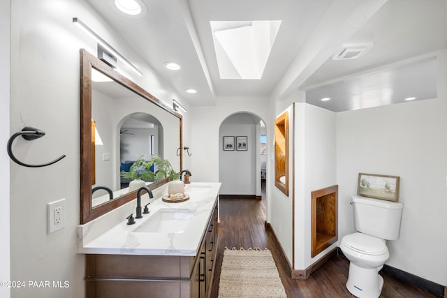 bathroom featuring vanity, hardwood / wood-style flooring, toilet, and a skylight