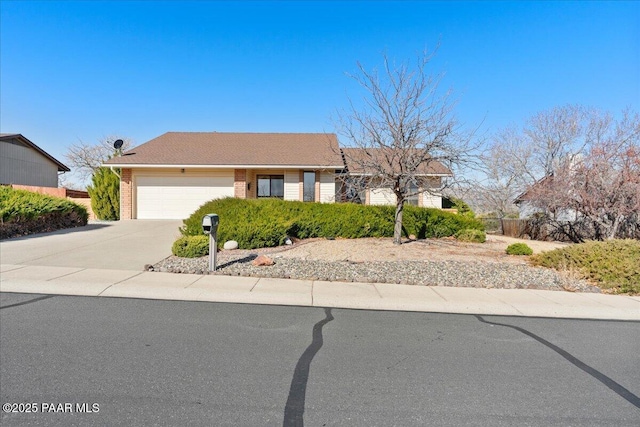 single story home with brick siding, an attached garage, and concrete driveway