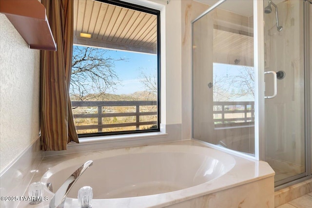 bathroom featuring a garden tub, a shower stall, and a textured wall