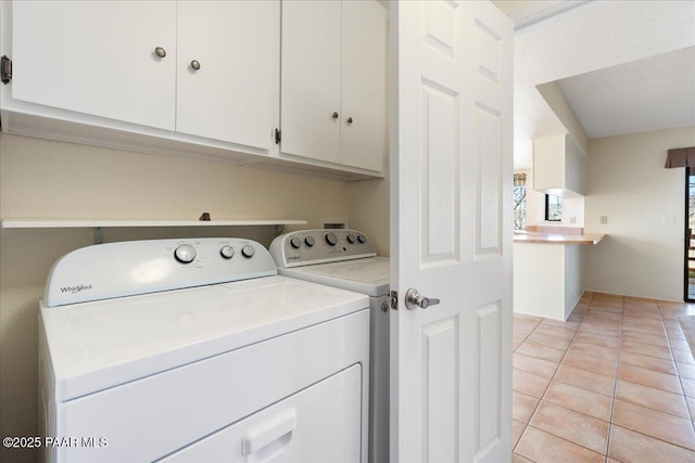 laundry area with washer and clothes dryer, light tile patterned floors, and cabinet space