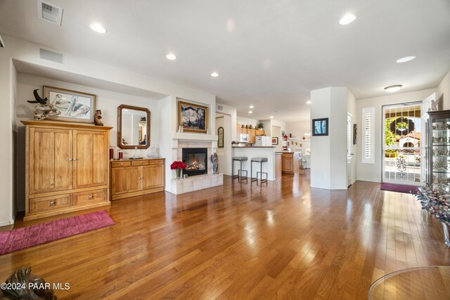 living room featuring a tile fireplace and light hardwood / wood-style flooring