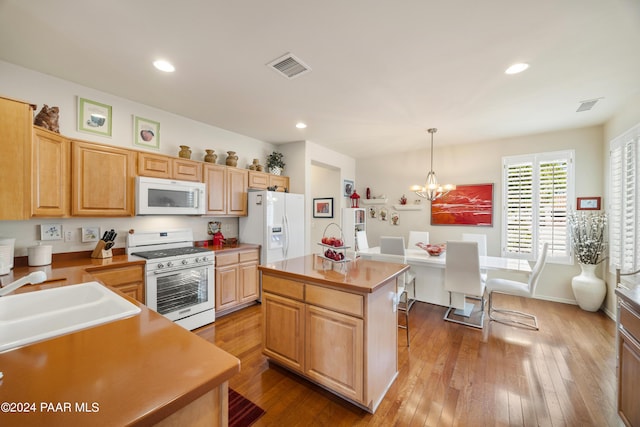 kitchen with white appliances, an inviting chandelier, light wood-type flooring, decorative light fixtures, and a kitchen island