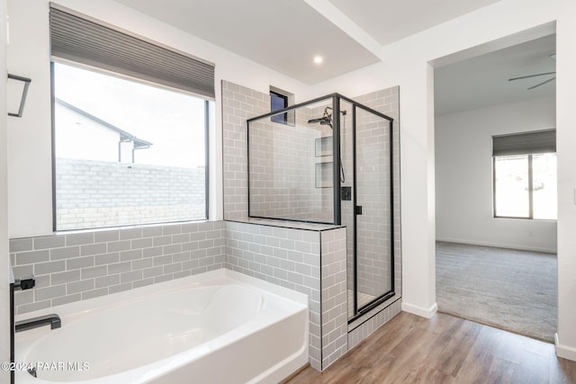 bathroom with a garden tub, baseboards, wood finished floors, and a shower stall