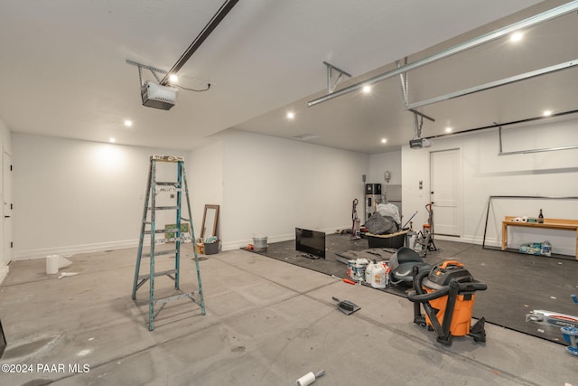 garage featuring hybrid water heater, baseboards, and a garage door opener