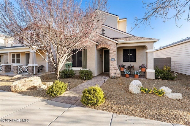 view of front of property with stone siding, central air condition unit, covered porch, and stucco siding