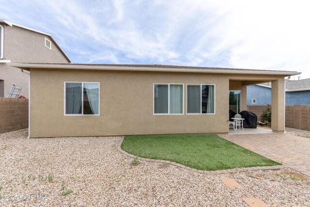 rear view of house with a yard, stucco siding, a patio area, and fence