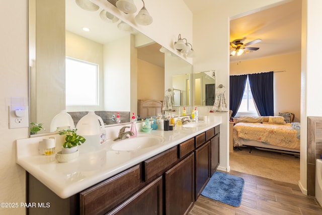 ensuite bathroom with wood finished floors, a ceiling fan, double vanity, and a sink