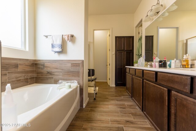 full bathroom featuring wood finished floors, a garden tub, and vanity