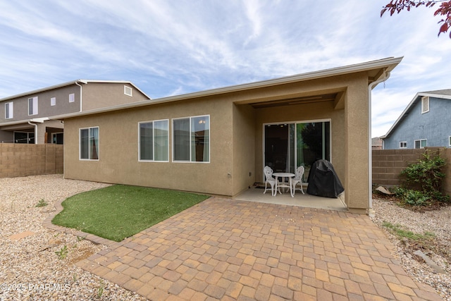 rear view of property featuring stucco siding, a patio, and a fenced backyard