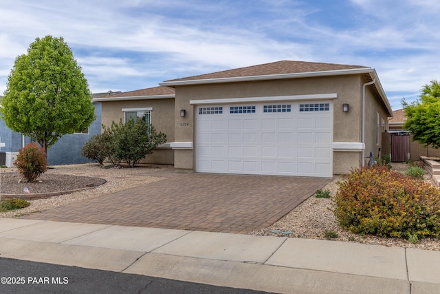 ranch-style house featuring stucco siding, decorative driveway, and a garage