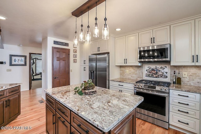 kitchen featuring stainless steel appliances, a center island, pendant lighting, and light hardwood / wood-style floors