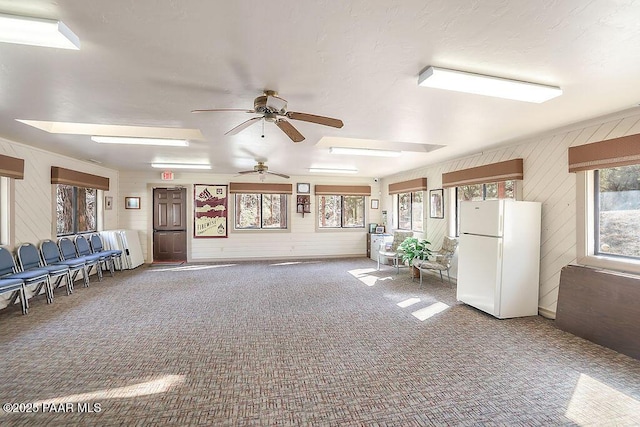 interior space with wood walls, ceiling fan, and carpet