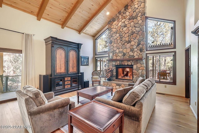 living room with a stone fireplace, wood ceiling, high vaulted ceiling, light wood-type flooring, and beamed ceiling