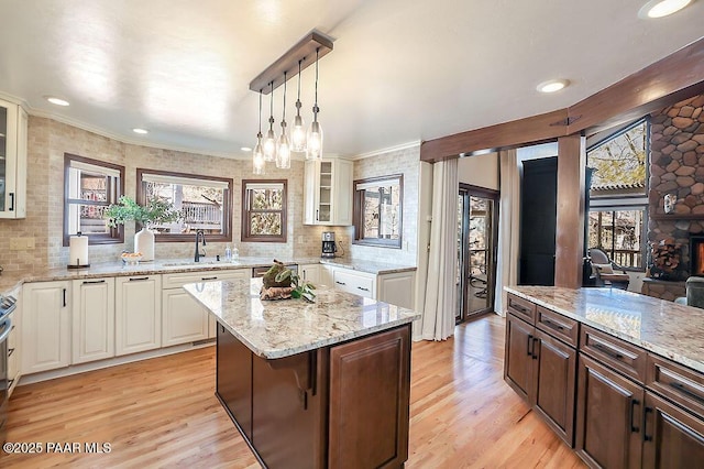 kitchen with hanging light fixtures, a kitchen island, sink, and dark brown cabinetry