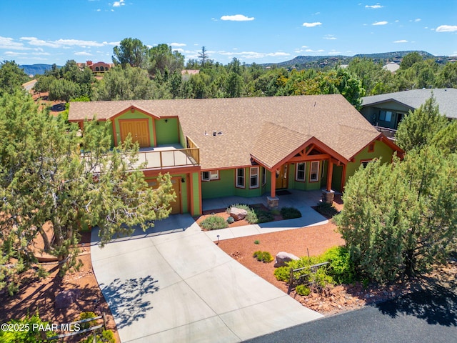 view of front of house featuring driveway, a shingled roof, and a balcony