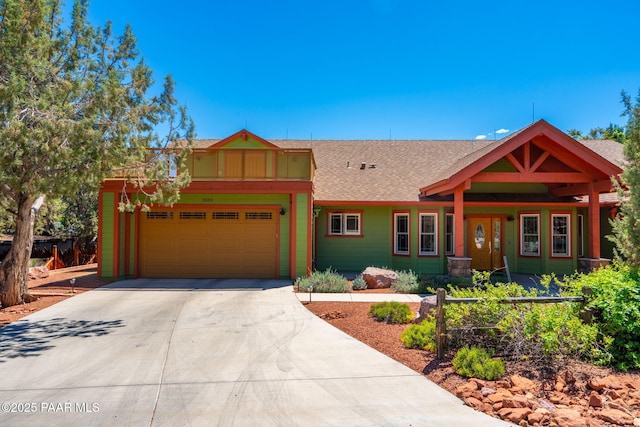 view of front of home featuring concrete driveway, a shingled roof, and a garage