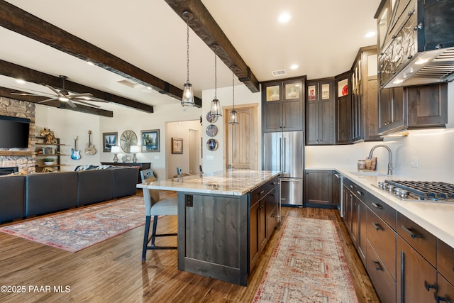 kitchen with beam ceiling, dark brown cabinets, stainless steel appliances, and a kitchen island